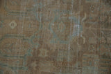Distressed pile of vintage Malayer rug with faded pale colors and visible foundation.