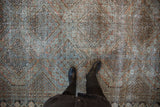 Distressed West Persian rug with faded terracotta, dusty teal, and brown multi-medallion pattern.