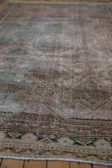 Texture detail of distressed West Persian rug, faded terracotta and dusty teal patterns, knot heads showing.