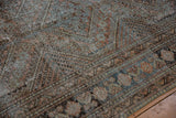 Faded Malayer border on distressed vintage West Persian rug, with terracotta, teal, and visible foundation.
