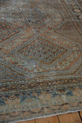 Distressed West Persian rug's faded terracotta, teal, brown pile with visible foundation wear.