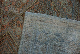Distressed West Persian rug pile in faded terracotta and teal, exposing hand knotted foundation.