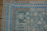 The corner of a vintage Hamadan rug with meandering floral borders in dusty blue and terracotta.