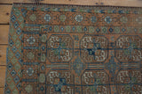 Distressed Afghani Belouch rug corner, geometric gul motifs and diamond border in copper, blue, green.