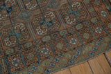 Distressed Afghani Belouch rug corner, geometric gul designs, chestnut, dusty blue, and olive green tones.