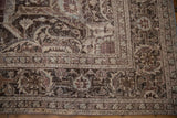 Distressed Khoy carpet corner displaying arabesque and floral motifs with faded brown and mauve tones.