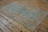 Distressed vintage Afghani Belouch rug; pale sky blue geometric guls on a worn beige field.