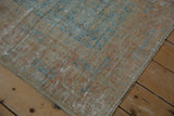 Distressed corner of the rug, with visible pale sky blue geometric motifs and textured wear.