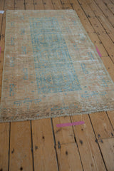 Secured end of distressed Belouch rug, showing worn geometric motifs in pale blue and terracotta.