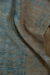 Distressed Belouch rug pile texture with geometric guls in pale blue and terracotta.