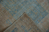 Folded corner of distressed Afghani Belouch rug, showing worn blue geometric pile, visible foundation.