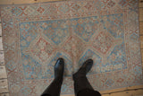 Distressed vintage Shiraz rug with faded blue, terracotta, and ivory floral patterns.