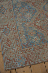 Distressed vintage Shiraz rug corner showing sky blue and terracotta geometric designs.