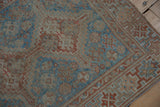 Faded blue and terracotta floral pinwheel motifs on a distressed vintage Persian Shiraz rug.