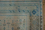 Distressed vintage Afshar rug corner: geometric diamond outlines in pale sapphire blue and silver.