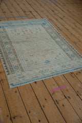 Distressed corner of a vintage Afshar rug, light blue geometric border, faded pile and visible foundation.