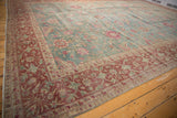 Angled corner view of a vintage Yezd carpet showing its burgundy floral border and distressed blue field.