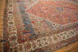 Angled view of an antique Bakshaish carpet corner showing the stepped medallion outline and bold color abrashes.