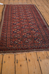 Vintage Belouch rug close-up: mostly secure fringe, geometric guls, and visible pile wear.