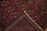Folded vintage Belouch rug: geometric guls in wine red, navy; original selvage and subtle wear.