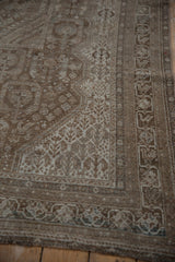 Distressed vintage Shiraz rug corner showcasing faded coffee brown and antique ivory patterns.
