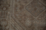 Distressed texture of the vintage Shiraz carpet, with stepped geometric motifs in brown and dusty teal.
