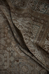 Distressed vintage Shiraz rug folds, with geometric relief in coffee brown, ivory, and dusty teal.