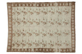 A vintage distressed Oushak carpet with repeating floral sprays in coffee brown and seafoam green on an ivory field.
