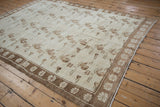 Angled view of a distressed Oushak carpet, detailing the repeating floral motifs and simplistic border.
