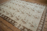 Angled view of a vintage Oushak rug, showing the distressed low pile and repeating floral motifs.