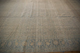 Distressed Persian Tabriz rug corner with blue floral border and beige Herati field.