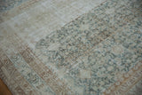Heavy abrashes and textured wear on vintage Malayer carpet in ivory, pale teal, and brown.