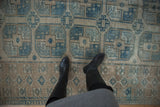 Distressed Ersari carpet with geometric guls, serrated borders, dusty blue, and beige tones.