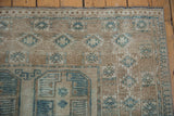 Geometric motifs in dusty blue and sand on a distressed vintage Ersari carpet pile.