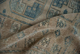 Distressed vintage Ersari carpet showing geometric flowers and worn pile in dusty blue and sand tones.