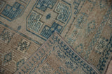 Distressed Ersari rug's geometric pattern, worn pile, hand-knotted back, and dusty blue tones.