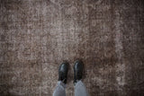 Distressed texture of vintage Sparta carpet, brown and charcoal overdyed tones with visible foundation.