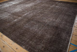 Distressed brown and charcoal Sparta carpet, showing faded vine patterns and secured selvage.