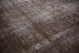 Close-up of vintage Sparta rug's distressed brown and charcoal pile showing exposed foundation.