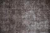 Distressed vintage Turkish Sparta carpet showing brown, charcoal, and visible foundation.