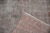 Close-up of distressed Sparta rug's worn ivory and dusty raspberry pile, exposing foundation.