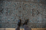 Distressed slate blue Turkish Sparta rug, showing faded brown floral and turquoise details underfoot.