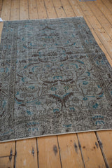 Distressed pile of a vintage Sparta rug featuring curvilinear floral patterns in slate blue and brown.