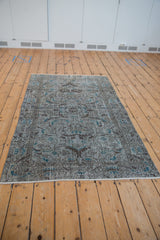 Distressed end of vintage Sparta rug with white fringe and worn pile.