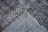 Folded distressed overdyed Sparta rug showing charcoal pile and visible woven foundation.