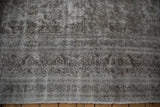 Vintage Meshed carpet edge with visible wear to foundation, short fringe, and muted silver-brown tones.