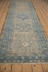 Angled view of a vintage Karaja runner showing its faded blue geometric pattern on an ivory field.