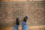 Distressed vintage Serab runner showing muted pink and aqua medallions on a beige field.