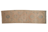 Distressed Persian runner with geometric diamond medallions in sky blue and dusty rose on a warm, neutral field.