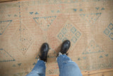 Low-pile texture of a distressed Persian runner with faded sky blue and blush geometric designs.